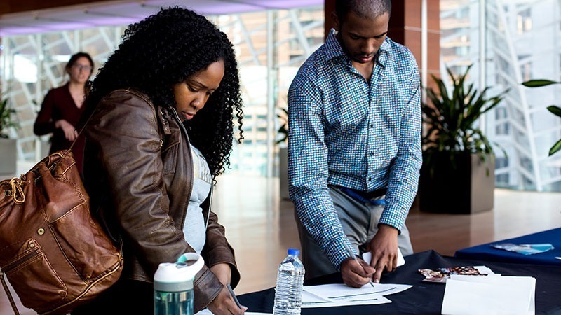 Two college aged students fill look at paperwork on a table at the Kimmel Center