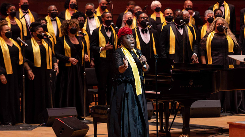 A singer in front of a choir performing on stage for A Soulful Christmas 