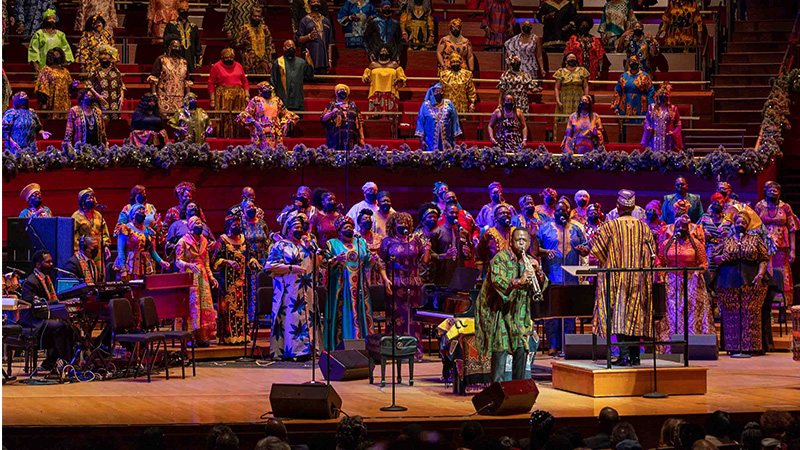 A musician performing in front of a choir on stage for A Soulful Christmas 