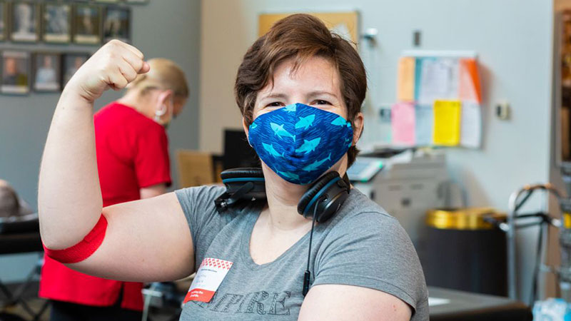 Masked Person gives thumbs up after donating blood