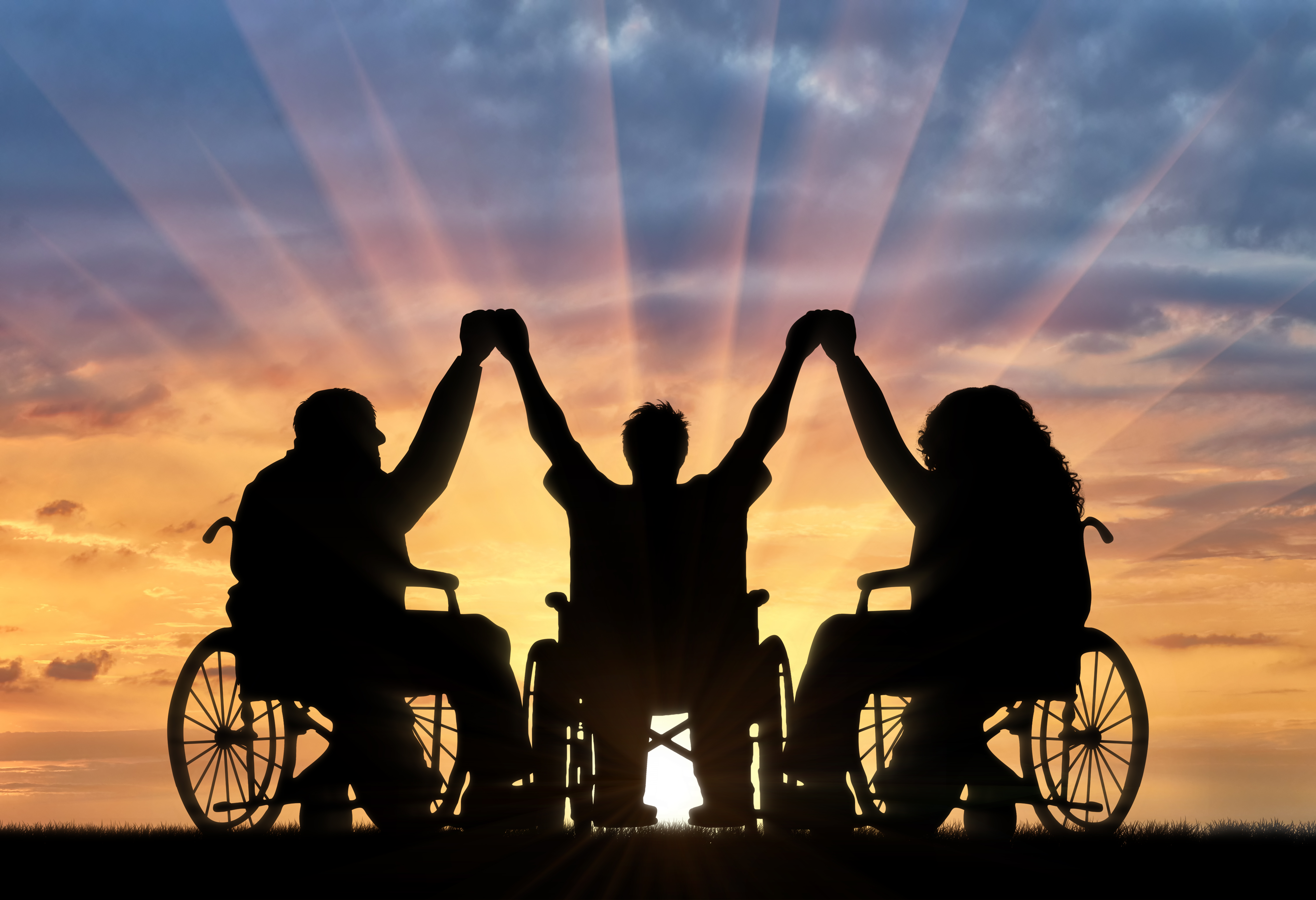 3 people in wheelchairs holding hands
