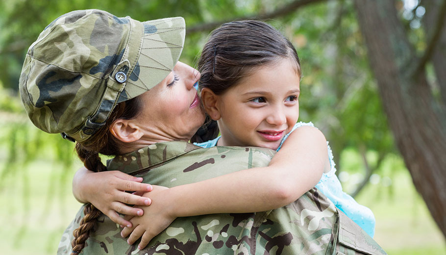 Young girl hugging her mother in military uniform