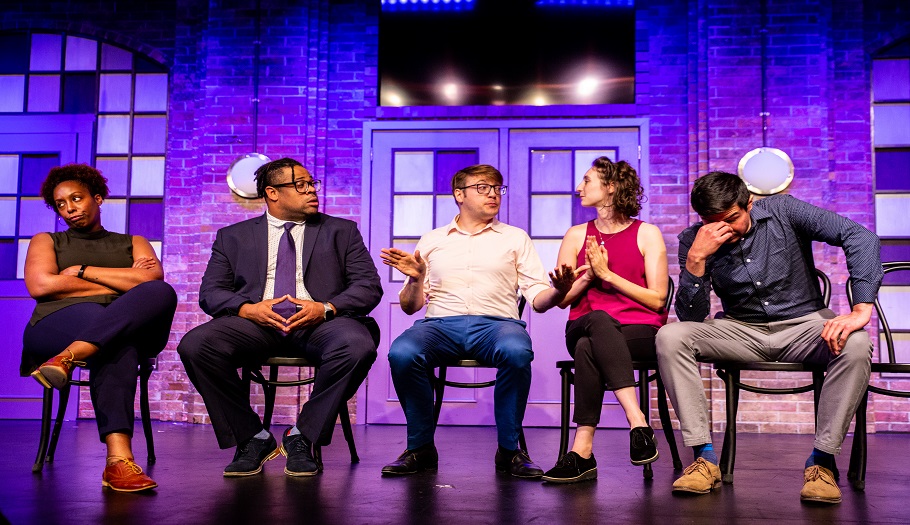 Second City comedian cast members sitting in chairs talking on stage