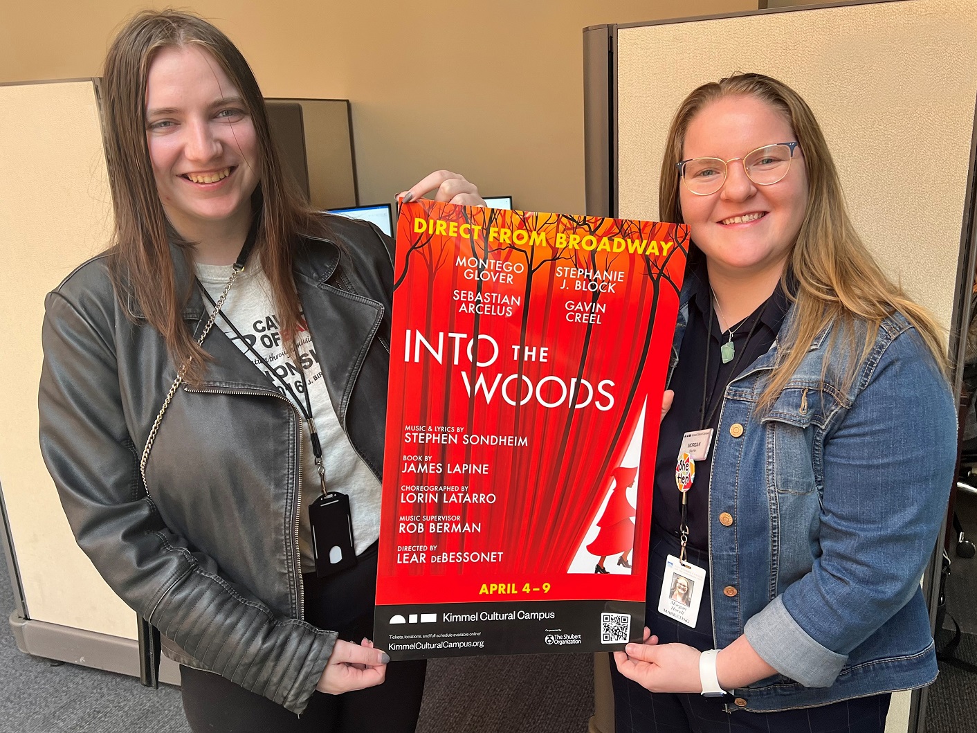 Two woman stand holding a poster for the 2022 production of Into The Woods