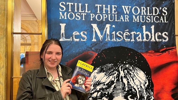 Drexel Co-op Intern Megan Rapp stands with a Les Miserables poster at the Academy of Music