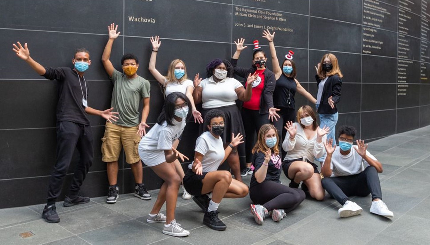 Students in a musical theater Kimmel Education program with masks pose for a group photo with jazz hands