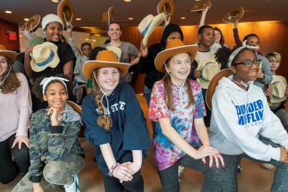 Students wearing cowboy hats pose grouped smiling