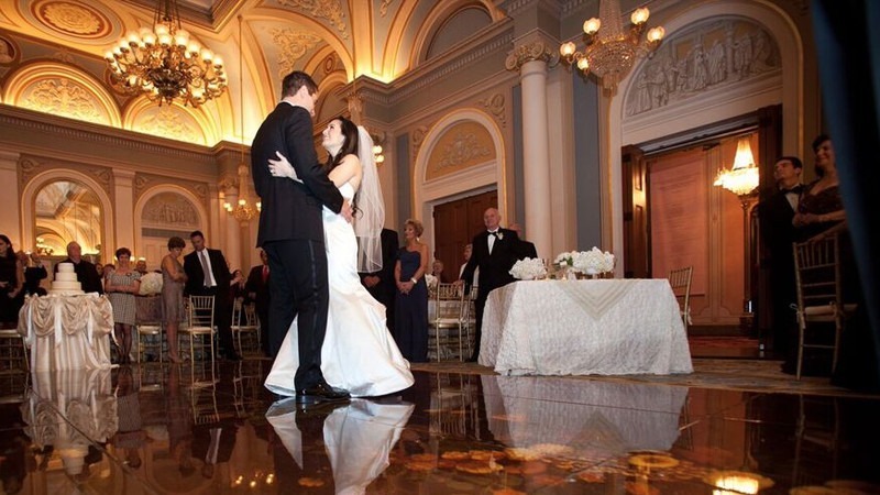 A bride and groom dance in the Academy of Music Ballroom as wedding guests look on.