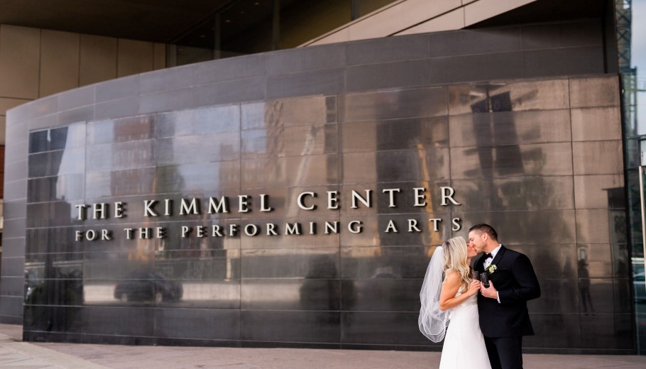 bride and groom in front of kimmel center drinking champagne